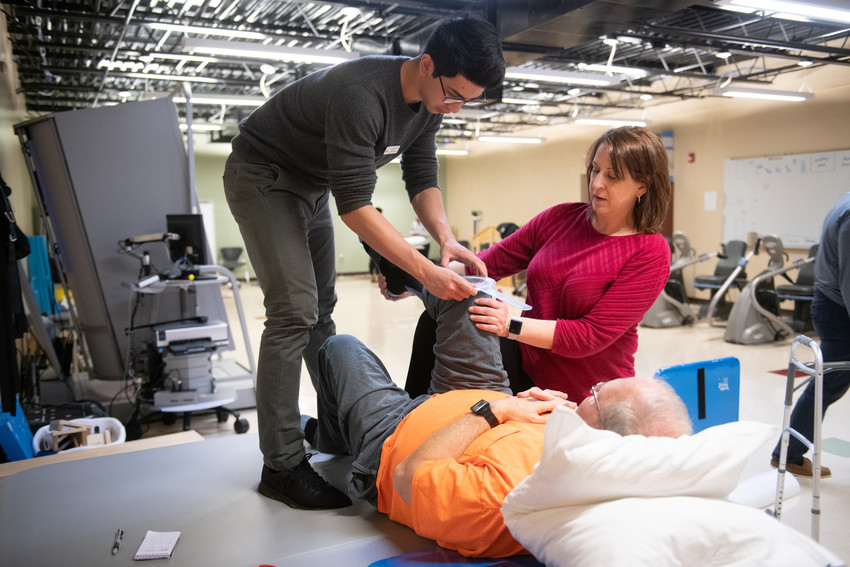 A professor and DPT student in the community health clinic working on a a patient.