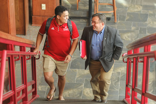 Jimmy Roux and a student walking up the stairs talking.