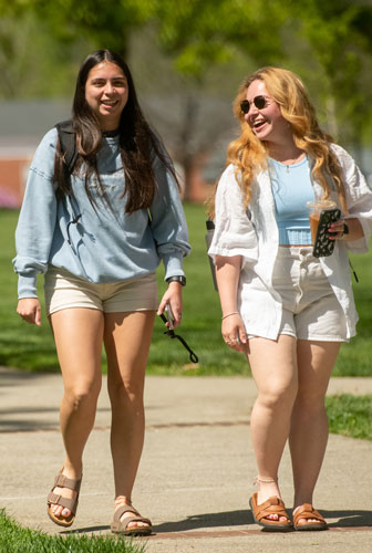 Two students walking and smiling on the Dell.