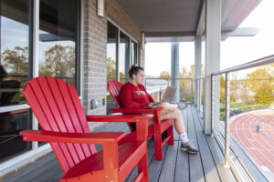Westover balcony with student sitting in a red chair.