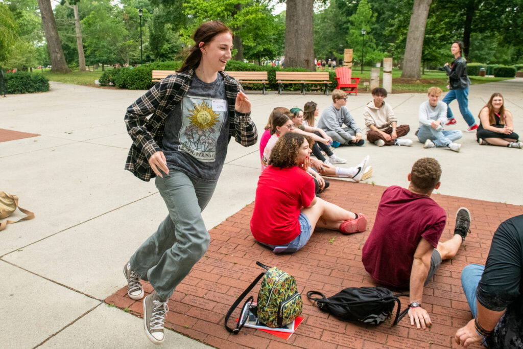 A girl runs in a circle around a group of people sitting outside